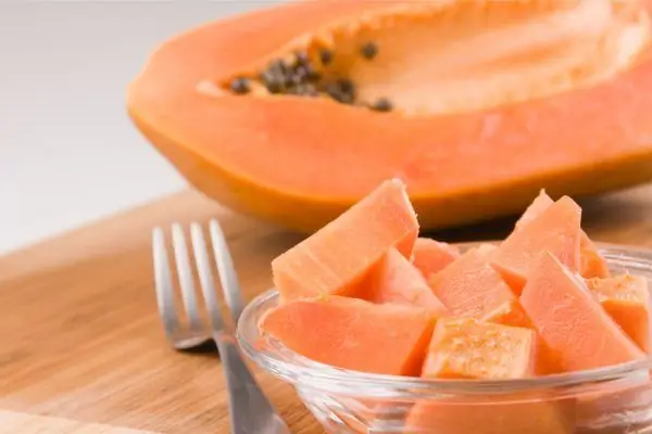 Gaffel og skiver papaya nær halvparten av frukten