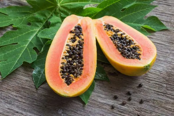 Skær papaya og spredte frø på bordet